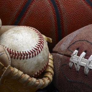 A baseball in a mitt, football and basketball